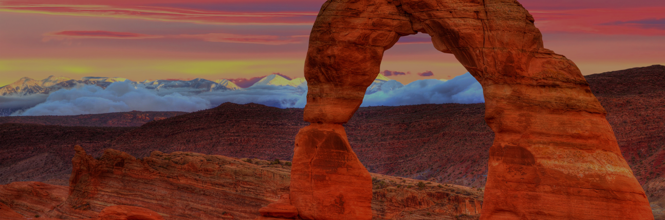 Delicate Arch at sunset with the Wasatch mountains in the background